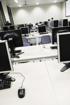 an empty computer lab with multiple monitors and keyboards