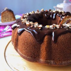 a bundt cake with chocolate icing and nuts on top