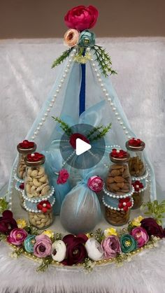 an arrangement of nuts and flowers on display in a pyramid with a blue ribbon around it