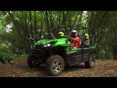 a man riding on the back of a green kawasaki four - wheeler in front of bamboo trees