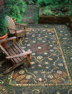 two wooden chairs sitting on top of a rug in the middle of a garden area