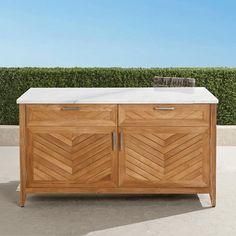 a wooden cabinet sitting on top of a cement floor next to a green planter