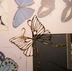 a butterfly sculpture sitting on top of a table next to some pictures with butterflies around it