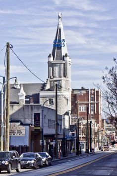 cars are parked on the street in front of an old building with a steeple