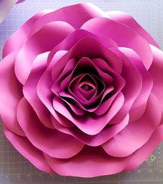 a large pink paper flower sitting on top of a cutting board next to some scissors