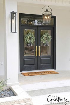 the front door is decorated with two wreaths and hanging from an iron chandelier