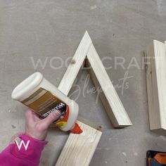 someone is using glue on wood to make a triangle shape with the letters v and w