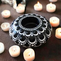 a black and white vase surrounded by lit candles