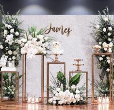 an arrangement of flowers and candles on display in front of a wall with nameplates