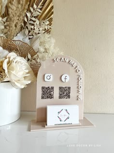 a white vase filled with flowers next to a phone and earring holder on top of a table