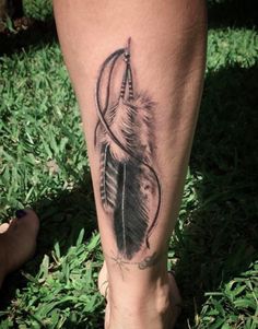 a woman's leg with a feather and arrow tattoo on her left side calf