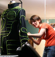 a woman standing next to a mannequin wearing an orange shirt