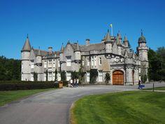 a large castle like building sitting on top of a lush green field next to a road