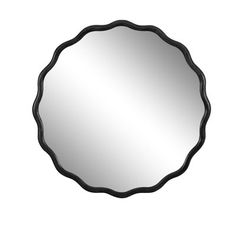 a round mirror on a white wall with black trimmings and an oval frame