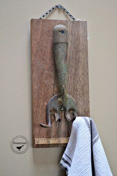 a towel hanging from a hook on a wall next to a piece of wood with an old metal handle