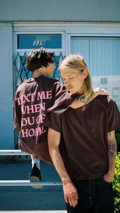 a man carrying a woman on his back in front of a building with the words text me when you're home written on it