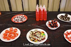 a table topped with plates of food next to bottles of juice and snacks on white plates