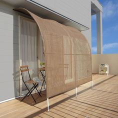 two chairs sitting on a wooden deck next to an awning over a patio area