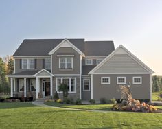 a large gray house sitting on top of a lush green field