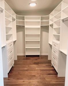 an empty walk in closet with white shelving and wood flooring on the wooden floor