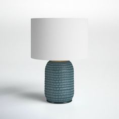 a blue ceramic table lamp with a white shade on the top and bottom part of it