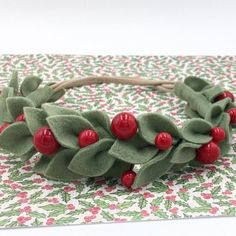 a wreath with red berries and green leaves on top of a white table cloth covered place mat