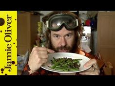 a man in goggles eating green beans with a plate on the table next to him