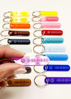 a hand holding a keychain with different colors and sizes on it in front of a white background