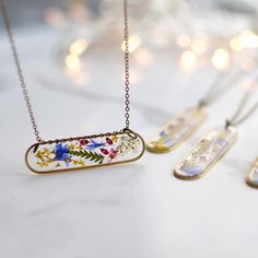 three necklaces with flowers on them sitting on a table