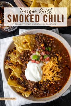 a bowl filled with chili, cheese and tortilla chips on top of a table