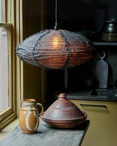 a lamp that is sitting on top of a table next to a vase and pitcher