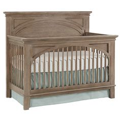 a wooden crib with white sheets on it