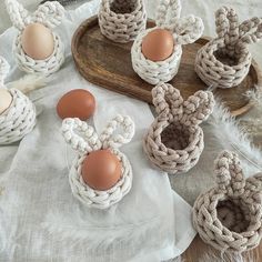 an assortment of crocheted baskets with eggs in them on a white table cloth