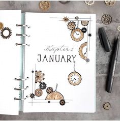 an open planner with gears on it next to some pens and other items that are scattered around