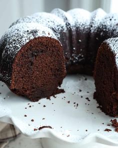 a chocolate bundt cake with powdered sugar on top and one slice cut out