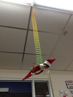 an elf is hanging from the ceiling with green and yellow spirals attached to it