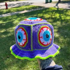 a person wearing a purple crocheted hat with eyeballs on it