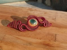 a red brooch sitting on top of a wooden table