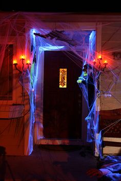 an entrance to a house decorated for halloween with blue and red lights on the front door