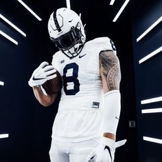 a football player in white uniform holding a ball and looking at the camera with his arm wrapped around him