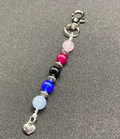 a keychain with several different colored beads and charms attached to it on a gray surface