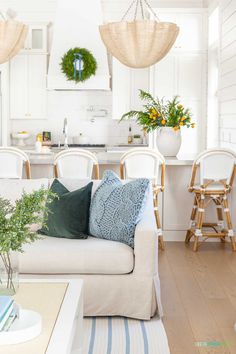 a living room filled with furniture and lots of greenery on the table in front of it