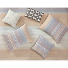 four pillows and two pillow cases on top of a striped bed sheet with an embroidered design