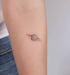 a small saturn tattoo on the arm