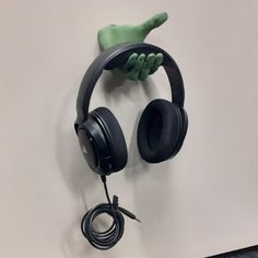 a pair of headphones hanging on the wall next to a hand holding a headset