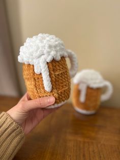 someone is holding up a crocheted beer mug