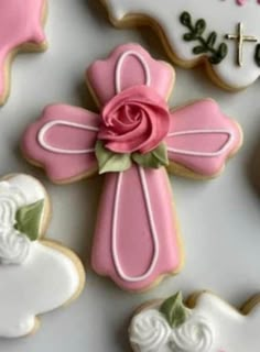 decorated cookies with pink and white icing are arranged in the shape of crosses, roses, and hearts