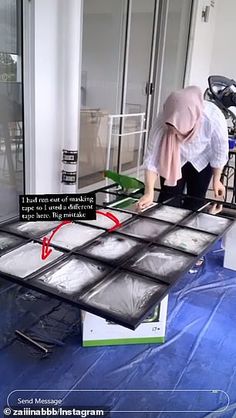 a woman is working on some kind of screen in front of a building with glass doors