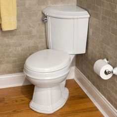 a white toilet sitting in a bathroom next to a wooden floor