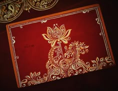 an intricately designed red and gold area rug next to a decorative wall hanging in a dark room